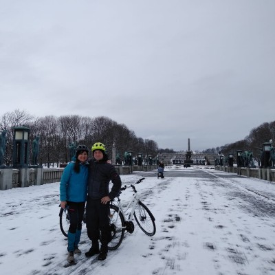 A couple pose with their bikes on a bridge in the snow